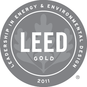 A circular gray badge with a leaf design and the words LEED GOLD 2011 in the center. The outer ring reads Leadership in Energy & Environmental Design.